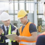 Workers discussing over clipboard in shipping yard